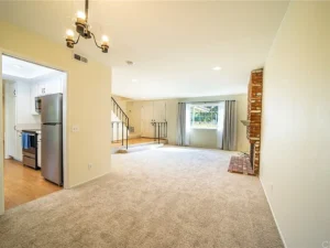living room with beige walls, carpet, and a brick fireplace