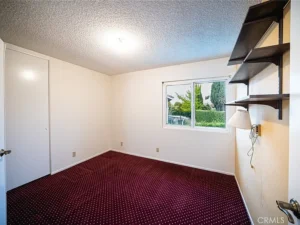 empty room with white walls and a maroon carpet
