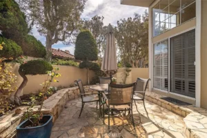 patio with stone flooring, round table with four chairs and an umbrella