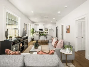 living room with gray sofas, pink-patterned pillows, and a wooden floor.