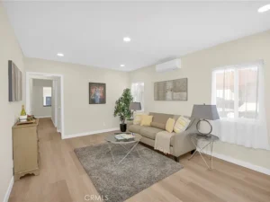 living room with a beige sofa, yellow cushions, and a gray rug on wooden flooring.