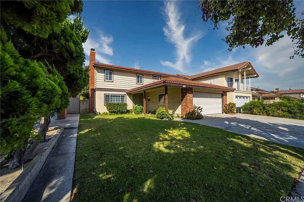 Two-story house with a red-tiled roof, brick accents, and a two-car garage.