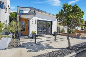 real estate white house with a dark roof, wood front door, and large glass windows