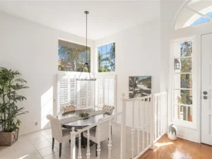 dining room with a dark oval table and beige chairs by a large window