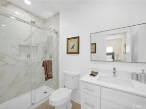bathroom with glass-enclosed marble shower, white vanity, and large mirror