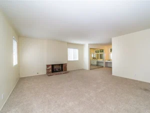 living room with beige carpet, white walls, and a brick fireplace