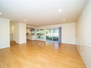 empty living area with light wood flooring and white walls.