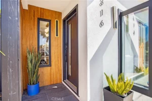 home entrance with a black door, wooden paneling, and large windows.