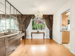 Room with a wooden piano on the left and large window.