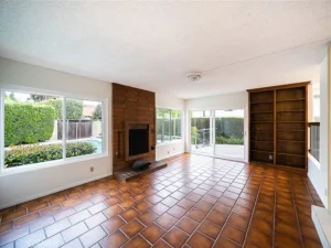 living room with a brick fireplace, wooden bookshelf, and a glass door