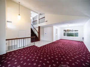 living room with red patterned carpet and white walls.