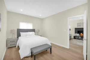 bedroom with beige walls, featuring a queen bed with white bedding and a gray headboard