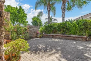 patio with potted plants, stone walls, and lush plants