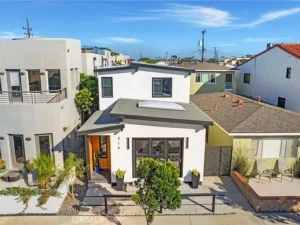 Real estate two-story white house with flat roof, surrounded by neighboring homes