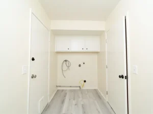 utility room with white walls and vinyl flooring.