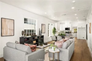 living and dining area with light gray sofas, abstract art, wood floors, and white cabinets.